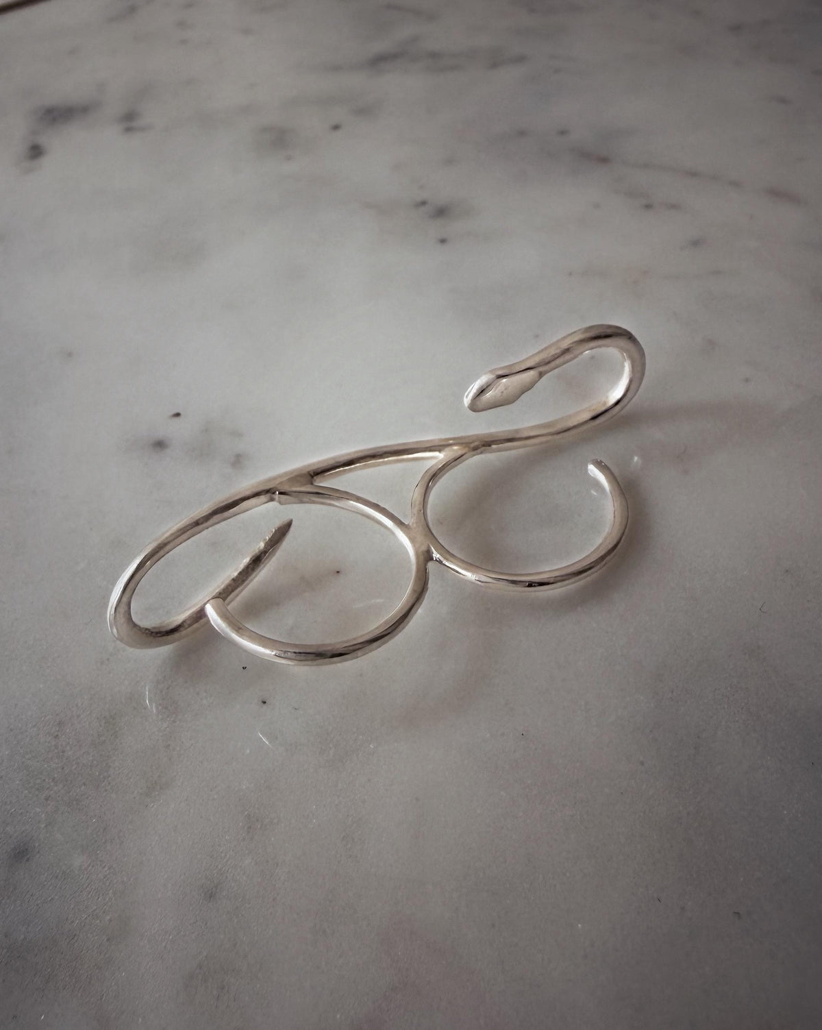 A Sterling silver 925  ring with a snake design. The ring curves over two fingers, creating an elegant and modern look.