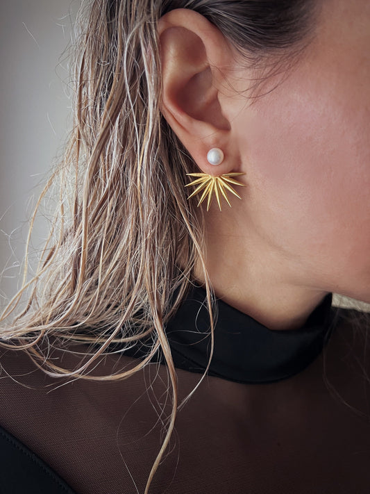 May include: Gold ear cuff earrings with a pearl accent. The earrings are designed to be worn on the upper part of the ear.